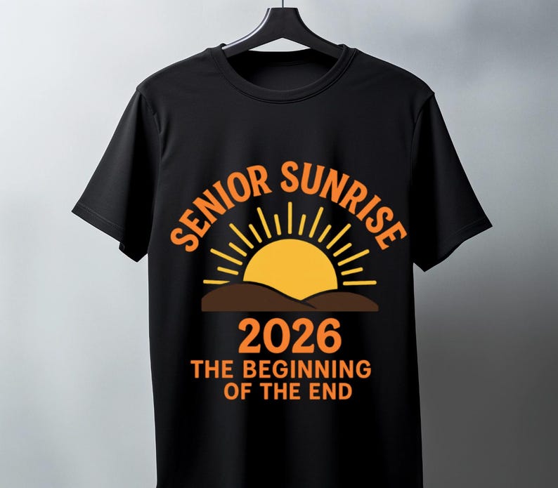 May include: Black t-shirt with the words "SENIOR SUNRISE" in orange arched above a yellow sun graphic. Below the sun is the year "2026" and the phrase "THE BEGINNING OF THE END" in orange. The shirt is hanging on a black hanger.