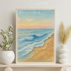 May include: Framed watercolor painting of a beach scene with blue ocean waves, a sandy shore, and a colorful sky. The artwork includes the text "If the sea rests at His word, so can I." The painting is displayed on a white shelf.