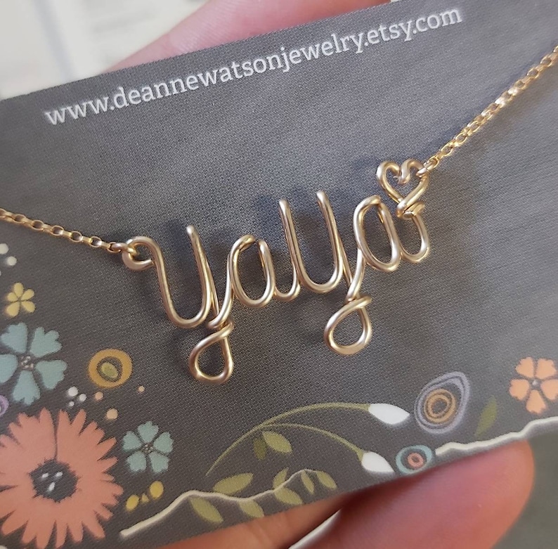 Pode incluir: Colar de fio de ouro com o nome "Y'all" escrito em it&aacute;lico com um pequeno cora&ccedil;&atilde;o no final do nome.