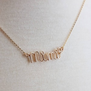 May include: A gold necklace with the word "mimi" spelled out in cursive.