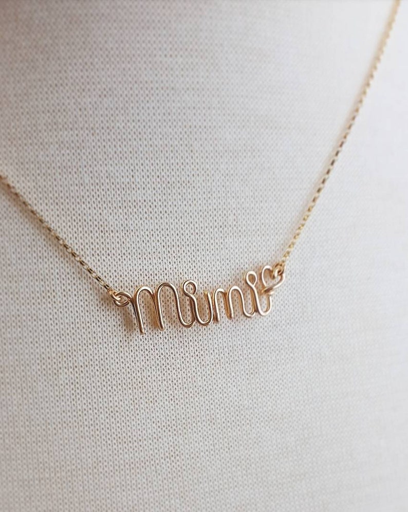 May include: A gold necklace with the word "mimi" spelled out in cursive.