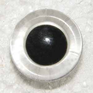 May include: A clear plastic eye with a black pupil, commonly used for craft projects.