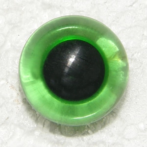May include: A green plastic eye with a black pupil. The eye is shiny and has a raised rim.