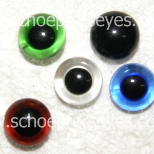 May include: Five different colored plastic googly eyes with black pupils. The colors are green, black, clear, blue, and red.