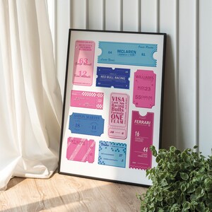 Op de afbeelding: Ingelijste print met gestileerde ticketontwerpen in roze en blauw, met Formule 1-raceteams en coureurs. Bevat teamnamen als Mercedes, McLaren en Ferrari, met coureursnummers en -namen. Een decoratief stuk voor racefans.