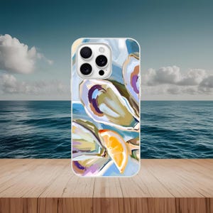 May include: A phone case featuring an abstract painting of oysters and a slice of orange. The artwork uses shades of blue, white, purple, and yellow. The case is on a wooden surface with a seascape background.