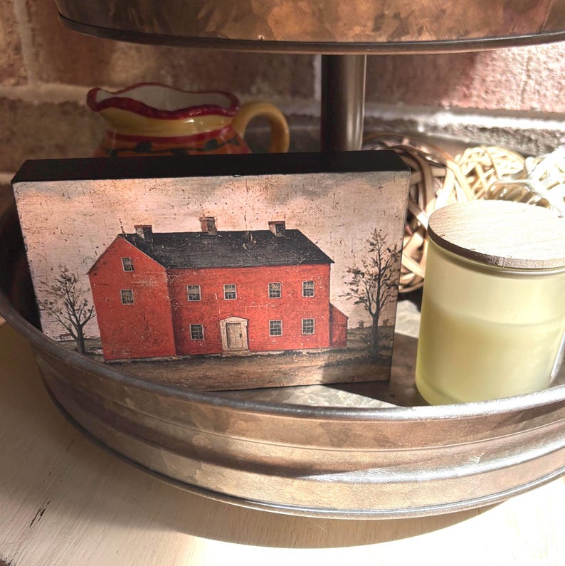 Primitive country decor block with red colonial farmhouse artwork, distressed vintage finish, and rustic Americana style displayed on a tiered tray.
