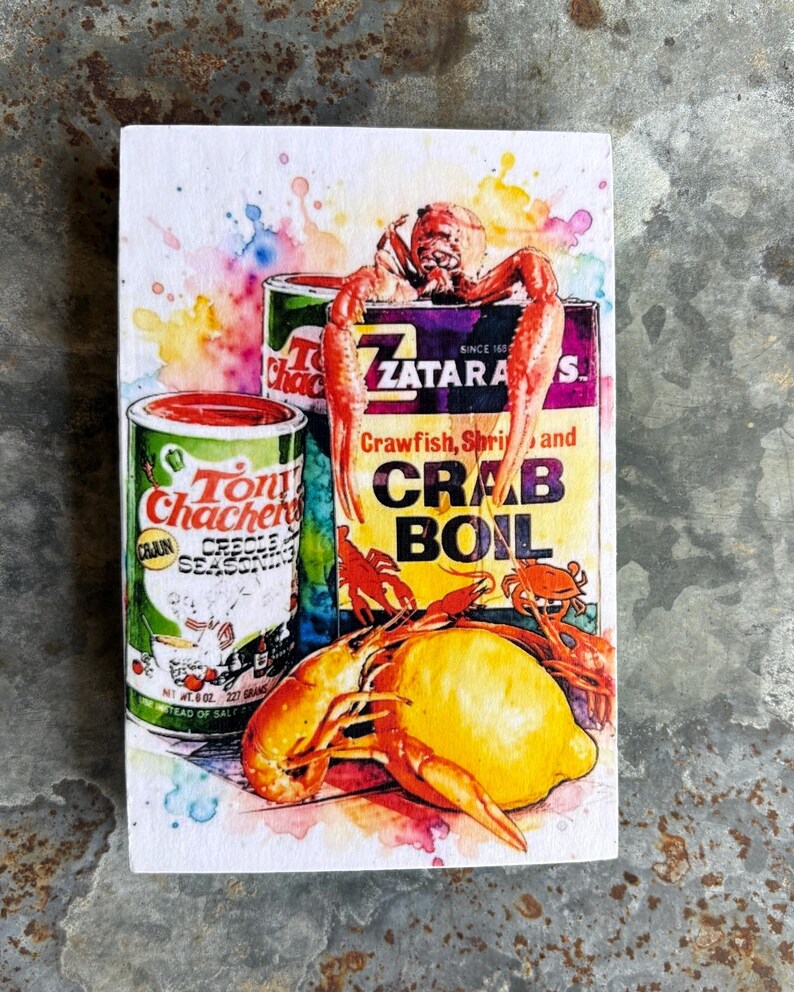 May include: Watercolor-style wood block featuring Tony Chachere's Creole Seasoning and Zatarain's Crab Boil boxes, with crawfish and a lemon. The image includes text: "Crawfish, Shrimp and Crab Boil". The seasoning can reads "Net Wt. 6 oz. 227 grams".