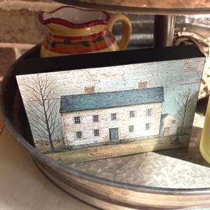 Primitive country decor block with white colonial farmhouse artwork, distressed vintage finish, and rustic Americana style displayed on a tiered tray.