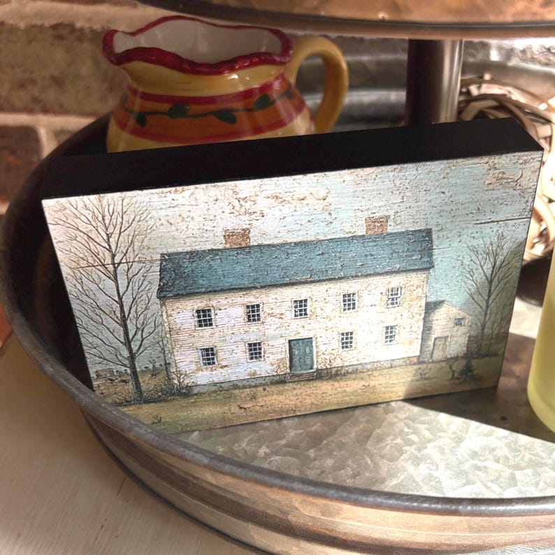 Primitive country decor block with white colonial farmhouse artwork, distressed vintage finish, and rustic Americana style displayed on a tiered tray.