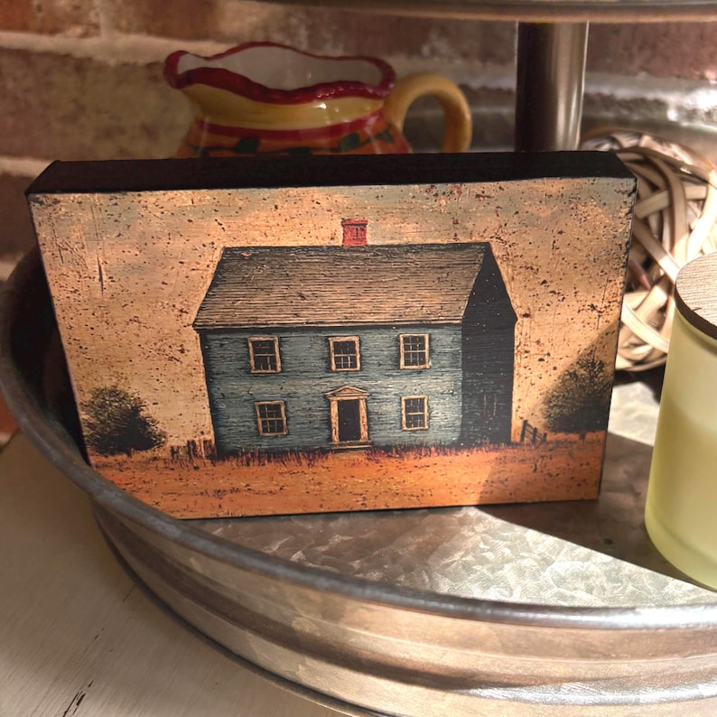 Primitive country decor block with blue colonial farmhouse artwork, distressed vintage finish, and rustic Americana style displayed on a tiered tray.