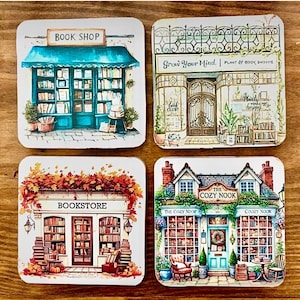 May include: A set of four square coasters featuring illustrations of storefronts. One shows a blue book shop, another a plant and book shop labeled Grow Your Mind, a third a bookstore with autumn leaves, and the fourth The Cozy Nook shop.