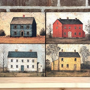 Four primitive Americana decor blocks displayed together on a wooden shelf against a rustic brick wall, featuring vintage colonial saltbox homes in distressed blue, red, cream, and mustard tones with early American farmhouse style.