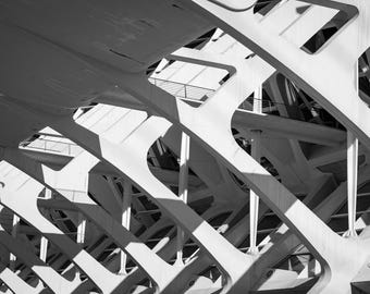 May include: Black and white architectural photograph featuring a complex network of intersecting, curved, and angled concrete structures. The design incorporates open spaces and geometric shapes, creating a play of light and shadow.