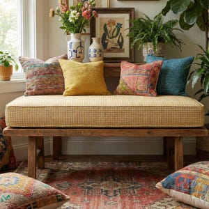 May include: A wooden bench with a yellow checkered cushion is adorned with colorful throw pillows. The pillows feature various patterns and textures, including woven and textured designs. The bench sits on a patterned rug, creating a cozy and inviting space.