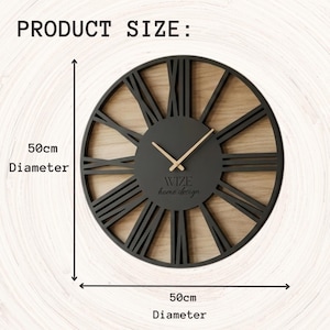 May include: A circular black wall clock with a light wood-effect centre and Roman numeral hour markers. The clock is 50cm in diameter. The text "WIZE home design" is visible. The clock hands are light wood-coloured.