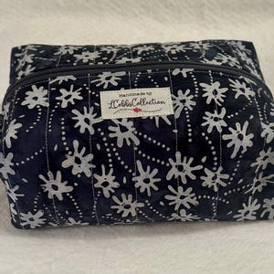 Bolsa de viaje para accesorios de maquillaje y cosméticos. Floral azul marino y gris. Cremallera gris estilo caja. Tejido de algodón acolchado.
