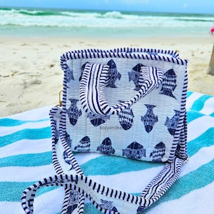 May include: A quilted tote bag featuring a white background with a repeating dark blue fish pattern. The bag has dark blue and white striped handles and trim, with a matching striped shoulder strap. The text kozyandka is visible on the front.