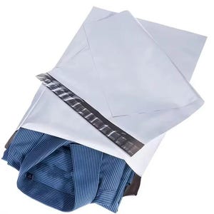 Peut inclure: Enveloppe postale blanche en polyéthylène avec une bande adhésive noire, partiellement ouverte pour révéler une chemise pliée à rayures bleues et blanches. La chemise est visible à l'intérieur.