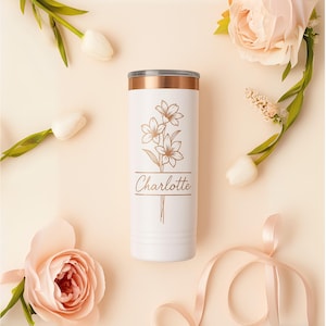 May include: White stainless steel tumbler with a rose gold lid and design. The design features a floral motif with three stylized flowers and the name "Charlotte" in a script font.