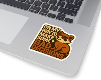 Könnte beinhalten: Ein Aufkleber mit einem Cartoon-Waschbären, der eine Sonnenbrille trägt und den Text "On my way to make some bad decisions".