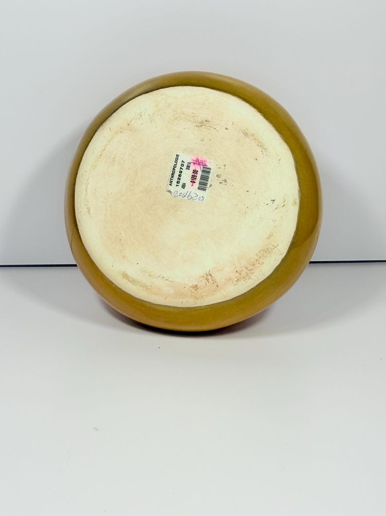 Peut inclure: Un bol rond en c&eacute;ramique avec un large bord brun dor&eacute; et un int&eacute;rieur de couleur cr&egrave;me. Le bol a une finition lisse et brillante. Le fond du bol est visible, avec une &eacute;tiquette comprenant le nom de la marque et un code produit.
