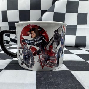 Puede incluir: Taza de cer&aacute;mica blanca con asa negra que presenta un collage de personajes de c&oacute;mics, incluyendo a War Machine, Bucky Barnes y Black Panther. La taza tiene la inscripci&oacute;n "FALCON REDWING".