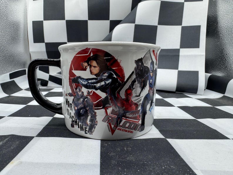 Puede incluir: Taza de cer&aacute;mica blanca con asa negra que presenta un collage de personajes de c&oacute;mics, incluyendo a War Machine, Bucky Barnes y Black Panther. La taza tiene la inscripci&oacute;n "FALCON REDWING".