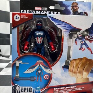 Pode incluir: Uma figura de a&ccedil;&atilde;o do Capit&atilde;o Am&eacute;rica numa caixa. A figura &eacute; azul, vermelha e branca, com um escudo e asas. A caixa apresenta o log&oacute;tipo da Marvel Studios e o texto "Captain America".