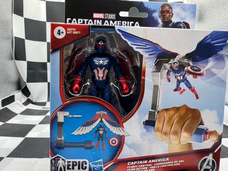 Pode incluir: Uma figura de a&ccedil;&atilde;o do Capit&atilde;o Am&eacute;rica numa caixa. A figura &eacute; azul, vermelha e branca, com um escudo e asas. A caixa apresenta o log&oacute;tipo da Marvel Studios e o texto "Captain America".