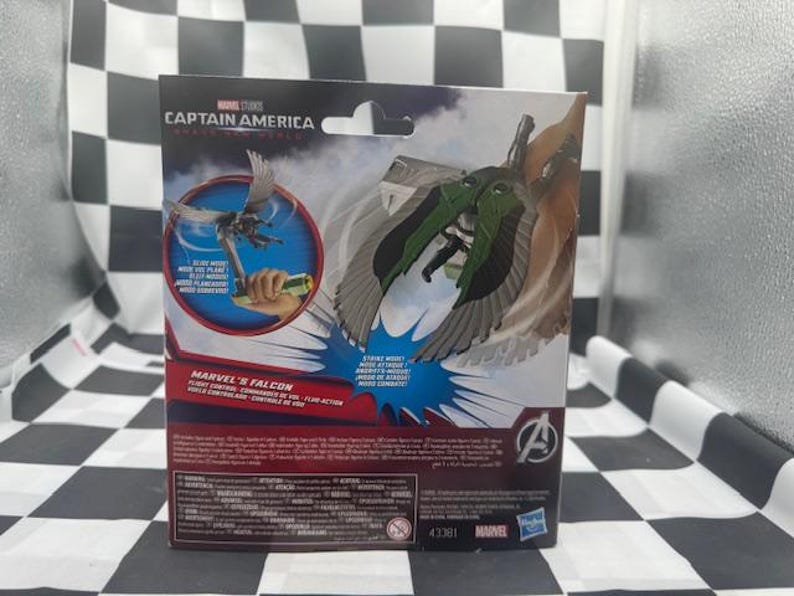 May include: Marvel's Falcon action figure packaging. The box features the Captain America logo and a depiction of the Falcon with green and gray wings. The packaging includes the Marvel logo and the number 43381.