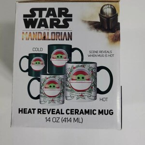 Pode incluir: Caneca de cer&acirc;mica Star Wars: The Mandalorian com revela&ccedil;&atilde;o de calor. A caneca apresenta um design com Grogu e o texto "Galaxy's Greetings". A caneca cont&eacute;m 414 ml de l&iacute;quido. O design muda com o calor.