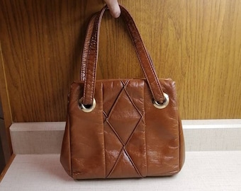 May include: A brown leather handbag with a diamond-shaped quilted pattern and gold-toned hardware.