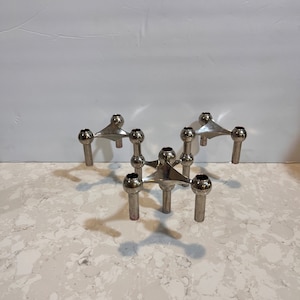 May include: Set of five silver candle holders with a star-shaped base and three arms. Each arm has a round ball at the end.