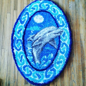 May include: A blue and white rug with a dolphin design. The rug is round and has a decorative border.