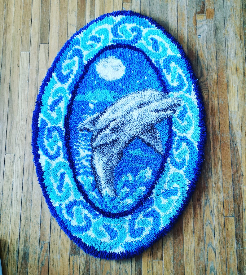 May include: A blue and white rug with a dolphin design. The rug is round and has a decorative border.