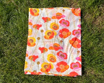 May include: A white fabric with a floral pattern featuring orange, red, and pink flowers. The flowers are stylized and have a retro look.