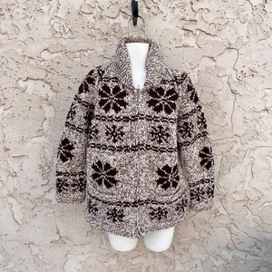 May include: A brown and white knit cardigan with a zipper closure and a snowflake pattern. The cardigan has a brown collar and brown pockets.