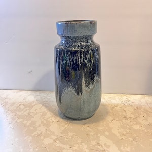 May include: A blue and black ceramic vase with a speckled glaze. The vase has a rounded body and a slightly flared opening.