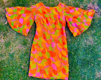 May include: A pink, orange, and green floral print dress with bell sleeves. The dress has a fitted bodice and a slightly flared skirt.