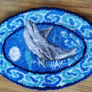May include: A blue and white oval rug with a gray dolphin design. The rug has a textured, fluffy surface.
