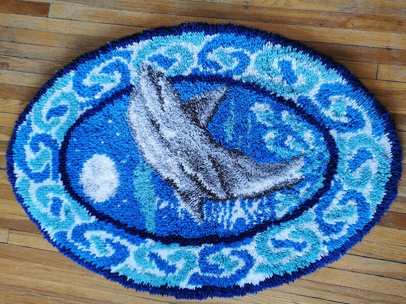 May include: A blue and white oval rug with a gray dolphin design. The rug has a textured, fluffy surface.
