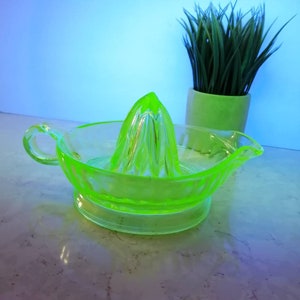 Peut inclure: Un presse-agrumes en verre vert vif avec un motif cannelé. Le presse-agrumes a une poignée et une base. C'est un ustensile de cuisine vintage.