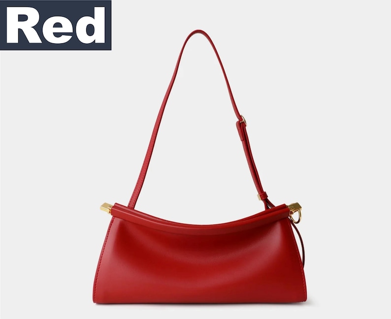 May include: A bright red handbag with a long, thin strap and gold-colored hardware. The bag has a rectangular shape with a curved top and a single handle. The word "Red" is in a white font on a dark blue background.