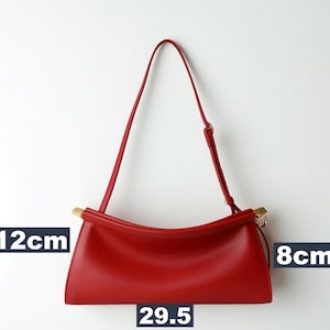 May include: A red handbag with a shoulder strap. The bag is 29.5 cm long, 12 cm high, and 8 cm wide. The bag has gold-colored accents on the handle attachments.