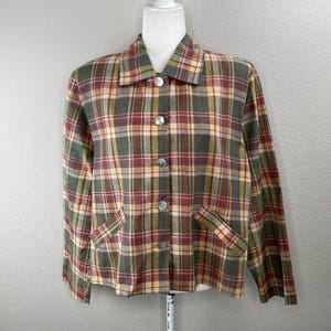 May include: A plaid button-up jacket in shades of red, green, yellow, and brown. The jacket has a collared neckline, long sleeves, and two front pockets. It is buttoned up with four round, pearlescent buttons.