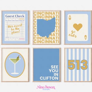 Puede incluir: Seis impresiones artísticas enmarcadas con detalles en azul claro y dorado. Las impresiones presentan un recibo, un mapa de Ohio, una carta de juego, una copa de martini, el texto "See You in Clifton" y el número 513.