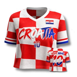 Może przedstawiać: Czerwono-biała koszulka piłkarska Chorwacji w kratkę z napisem "CROATIA" w kolorze białym i niebieskim oraz numerem "10". Koszulka ma dekolt w serek i niebieskie akcenty na rękawach. Widoczna jest r&oacute;wnież mniejsza koszulka z napisem "YOUR NAME".