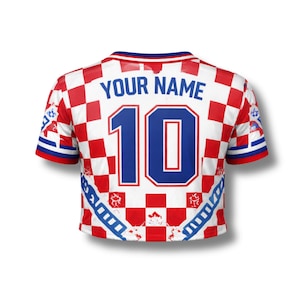 May include: Cropped soccer jersey with a red and white checkered pattern. The jersey features the number 10 in blue, with the text "YOUR NAME" above it. The sleeves have blue and white stripes.