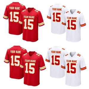 Pode incluir: Uma coleção de quatro camisas esportivas nas cores vermelho e branco. Cada camisa apresenta o número 15 na frente e nas costas, com espaços para texto personalizado rotulados como YOUR NAME e TEAM NAME em letras em negrito.